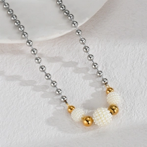 Macro detail of stainless steel ball chain with golden beads and white pearl cluster