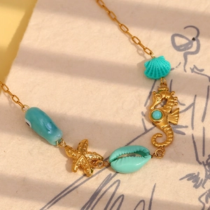 18K gold plated necklace with turquoise seahorse, starfish and shell pendants on art paper