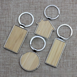 Detail of four geometric metal and bamboo wood keychains in round, house, and rectangle shapes