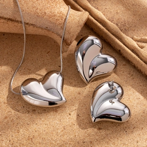 Polished silver heart jewelry set with necklace and earrings on a rustic background