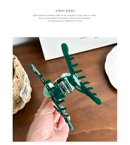 Macro detail of a large dark green tulip hair claw clip showing the internal spring