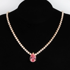 Detail of gold tennis necklace with pink pear-cut gemstone pendant on black mannequin
