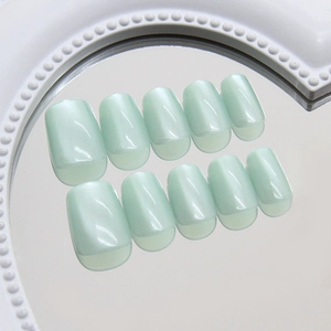 Mint green cat eye press-on nails in short square shape displayed on a round mirror