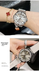 Close-up of a silver rhinestone watch with calendar display and gray leather strap