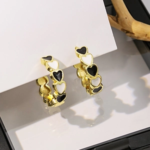 Détails macro des boucles d'oreilles maillons cœurs noirs et blancs en finition dorée
