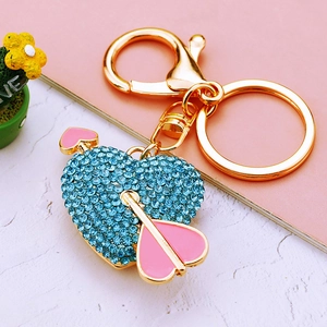 Golden heart keychain with blue rhinestones and pink arrow on marble background