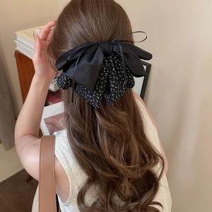 Detail of a large black leopard print bow scrunchie styled on brown wavy hair