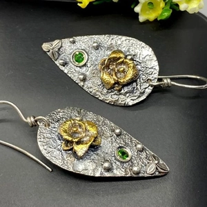 Vintage silver drop earrings with golden rose and green gemstone on black background