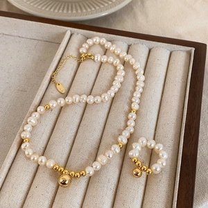 Gros plan d'une parure de bijoux en perles vintage sur un plateau en velours beige