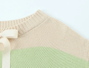 Detail of striped knit sweater showing cream grosgrain bow on shoulder and waffle texture
