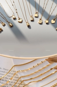 Close-up of gold titanium steel necklaces with heart locks and star charms in various textures