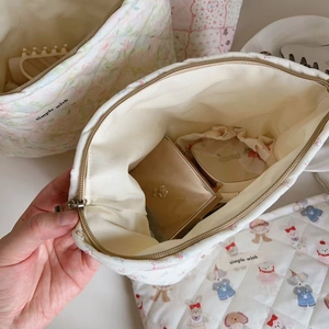 Detailed close-up of quilted cotton makeup bag with floral print and metal zipper closure