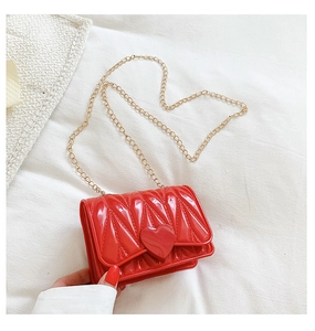 Detail of red glossy mini crossbody bag with heart buckle and gold chain strap