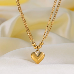 Double-layered golden heart bracelet with metallic beads on yellow silk background