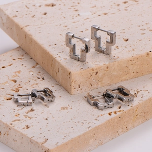 Detailed view of silver geometric hoop earrings with secure clasp on stone background