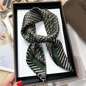 Carré en soie avec motif géométrique vert et rayures noires dans une boîte cadeau de luxe