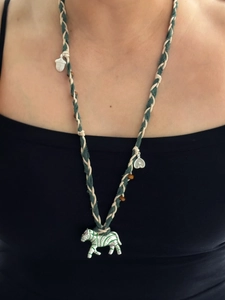 Détail d'un collier bohème en corde tissée avec pendentif zèbre argenté et touches vertes