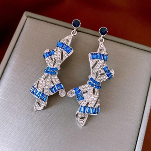 Detail of silver bow earrings with blue rectangular and clear round rhinestones