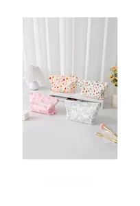 Set di quattro graziose borse da trucco da viaggio con motivi a fiori e cuori su tavolo