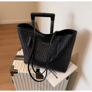 Close-up of black woven leather tote bag texture with slim shoulder strap design