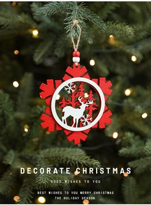 Close-up of wooden Christmas ornament with reindeer and cedar silhouette hanging on tree