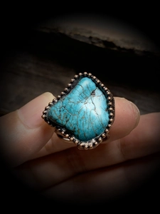 Detailed view of an irregular turquoise stone set in a vintage bronze adjustable ring