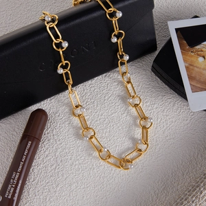 Classic 18K gold-plated stainless steel chain necklace with white pearls on a textured background