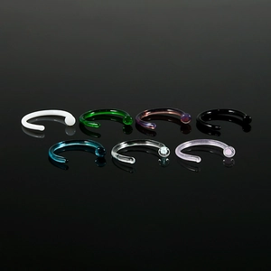 Collection of seven colorful C-shaped nose rings in acrylic on reflective black surface