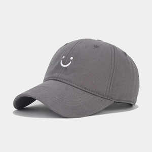 Close-up of white smiling face embroidery on a dark grey cotton twill baseball cap