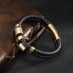 Braided black leather bracelet with golden magnetic clasp on a dark textured background
