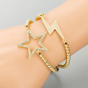 Detail of 18K gold-plated beaded bracelets with star and lightning pendants on wrist