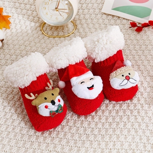 Rote Weihnachts-Babysocken mit 3D-Weihnachtsmann und Rentier auf Strickdecke