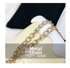Detail of a polished gold metal chain strap featuring classic oval links for handbags