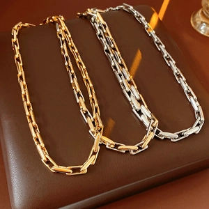 Flat lay of gold and silver rectangular link chain necklaces on brown leather surface