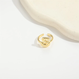 Close-up of golden adjustable ring featuring a 3D letter S on a ceramic plate