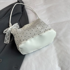 Polka dot bucket bag in white with lace bow detail and dark blazer background