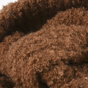 Close-up van zachte bruine krullende pluche textuur voor warme winter gebreide muts