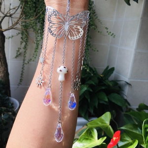 Detail of silver butterfly suncatcher with crystal prisms reflecting light on hand