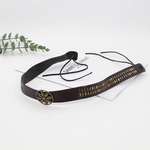 Detail view of brown leather hat band with bronze floral ornament and square metal studs