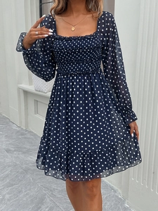 Detail of navy blue polka dot dress featuring a square neckline and ruffled hemline