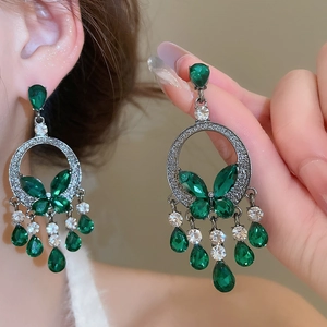 Detailed close-up of emerald butterfly tassel earrings with silver drop gems and crystals