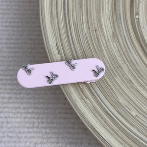 Close-up of pink hair clip with silver bow ornaments on a cozy knit background