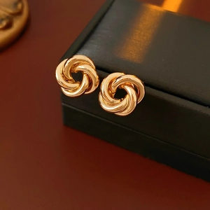 Detailed macro shot of gold knotted earrings resting on a black jewelry gift box
