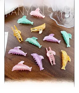 Detailed macro view of four glittery dolphin-shaped hair claws in pastel candy colors