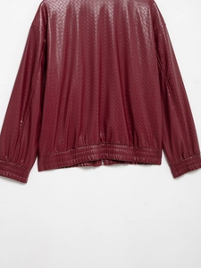 Macro shot of burgundy woven faux leather texture and hem detail on a bomber jacket
