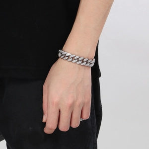 Gros plan du bracelet gourmette argenté serti de strass porté au poignet d'un modèle
