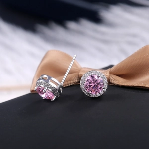 Macro shot of silver round halo stud earrings with pink zircon and white accent stones