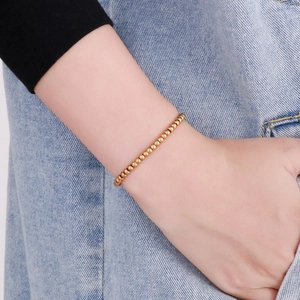 Close-up of a minimalist golden beaded bracelet with lobster clasp on a female wrist