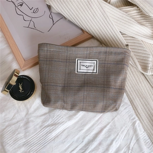 Detailed macro view of vintage brown plaid makeup bag featuring a Time to Party fabric label