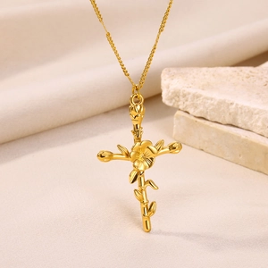 Detailed macro view of golden vine cross pendant with leaves on textured background